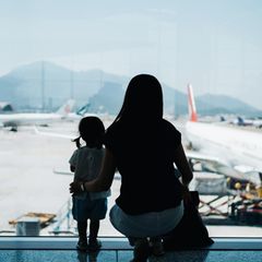 Auswandern mit Familie: Eine Mutter steht mit ihrem Kind am Flughafen