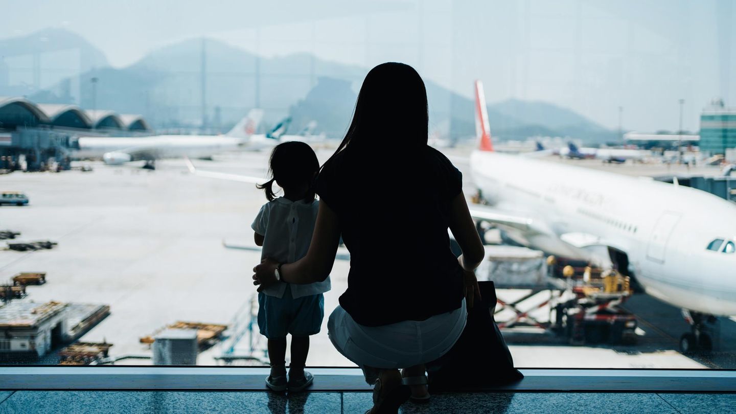 Auswandern mit Familie: Eine Mutter steht mit ihrem Kind am Flughafen Auswandern mit Familie: Eine Mutter steht mit ihrem Kind am Flughafen