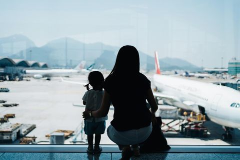 Auswandern mit Familie: Eine Mutter steht mit ihrem Kind am Flughafen