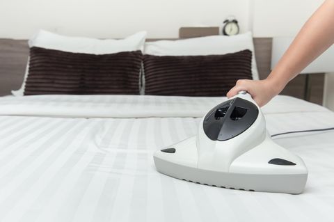 Deal News: Eine Frau reinigt eine Matratze mit einem Milbensauger