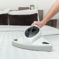 Deal News: Eine Frau reinigt eine Matratze mit einem Milbensauger