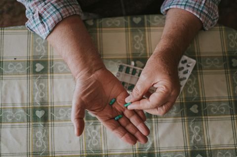 eine ältere Person hält Tabletten in den Händen
