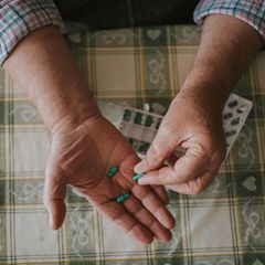 eine ältere Person hält Tabletten in den Händen