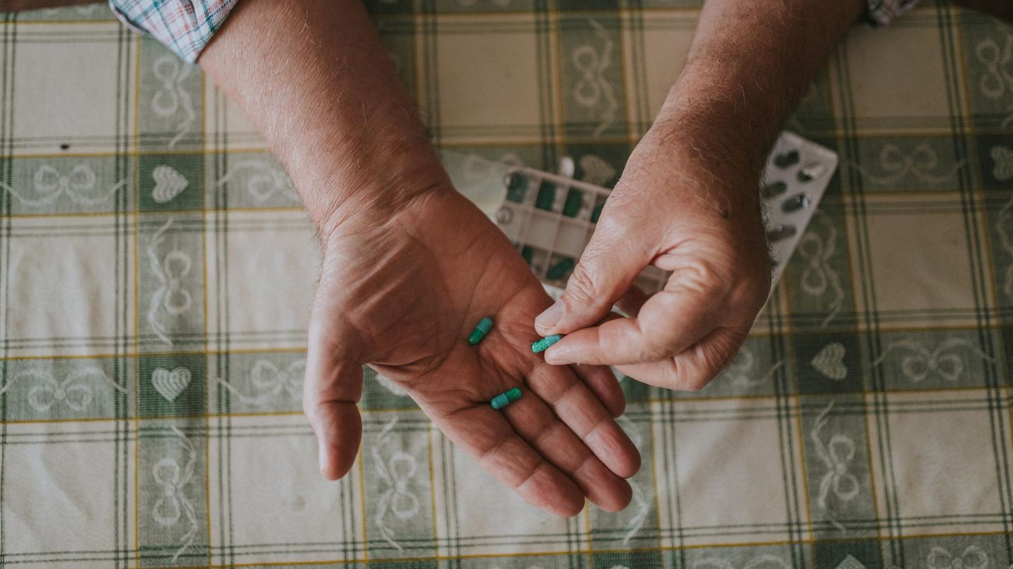 eine ältere Person hält Tabletten in den Händen