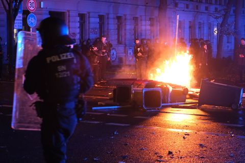 Polizisten stehen auf der Eisenbahnstraße in Leipzig vor brennenden Gegenständen. Foto: Sebastian Willnow/dpa
