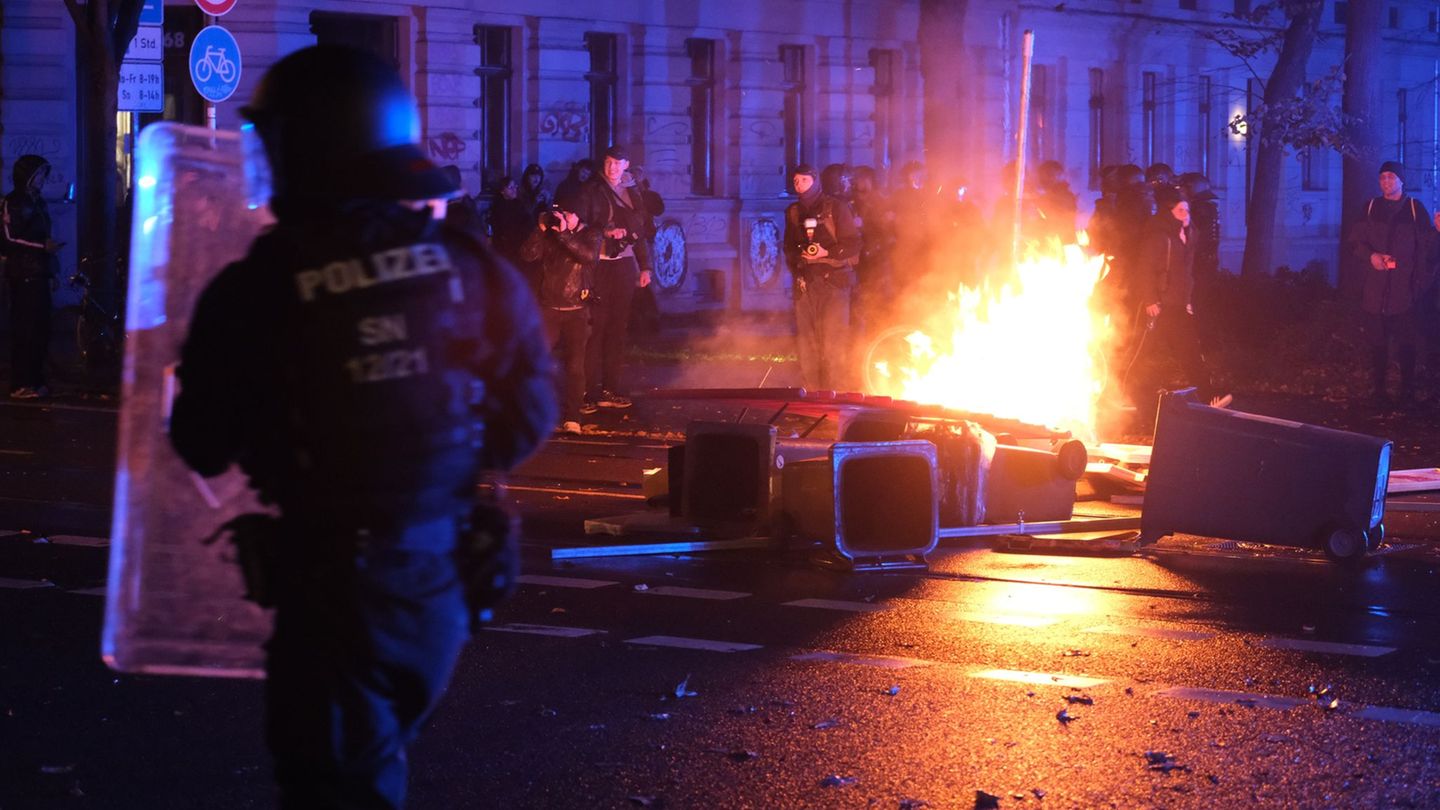 Polizisten stehen auf der Eisenbahnstraße in Leipzig vor brennenden Gegenständen. Foto: Sebastian Willnow/dpa
