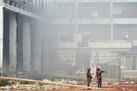 Feuerwehrmänner im zerstörten Frachtkomplex des Flughafens