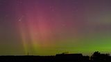 Brandenburg, Deutschland. Am Nachthimmel leuchten der Komet Lemmon "C/2025 A6" (Bildmitte links) und die Polarlichter. Letztere werden durch eine Wolke elektrisch geladener Teilchen eines Sonnensturms in der Erdatmosphäre erzeugt