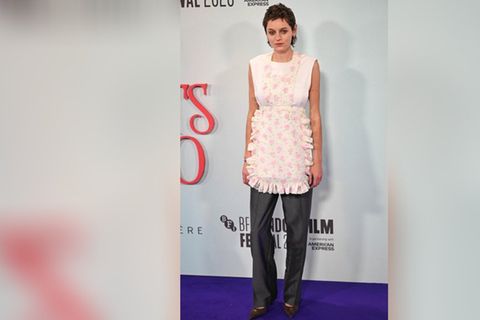 Schauspielstar Emma Corrin mit Blumenschürze auf dem roten Teppich.