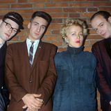 Annette Humpe posiert mit ihrer Band IDEAL vor einer Backsteinmauer