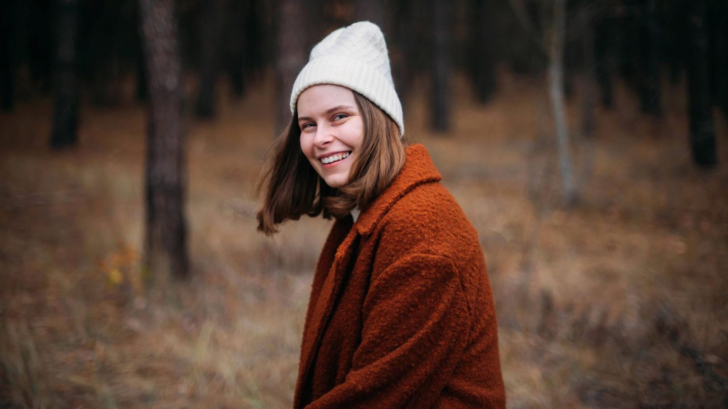 Eine Frau steht im Wald. Sie lächelt in die Kamera. Eine Frau steht im Wald. Sie lächelt in die Kamera.