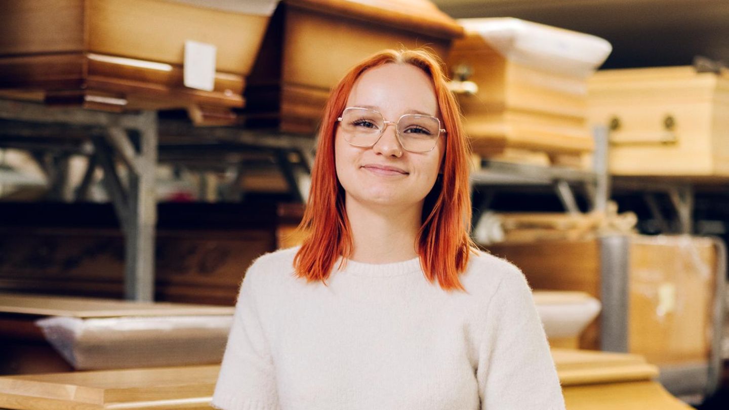 Werdende Bestattungsfachkraft Jocelyn Zschächer steht vor Särgen