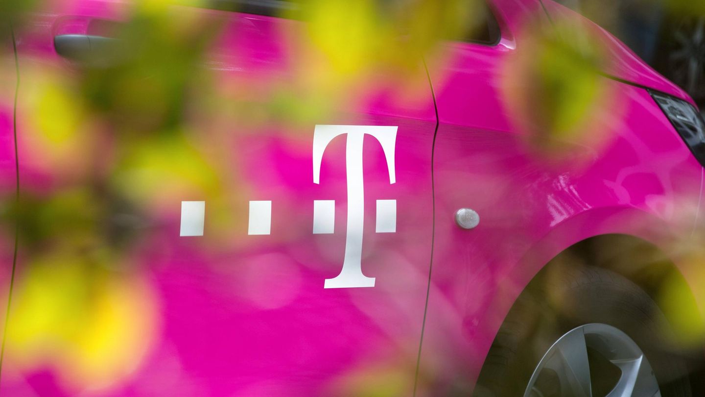 Magentafarbenes Fahrzeug der deutschen Telekom mit Firmenlogo hinter einer Hecke
