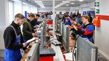 Gewerblich technisch Auszubildende stehen in einer Reihe und hantieren mit Kabeln