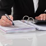 Eine Frau überprüft mit einem Taschenrechner Rechnungen