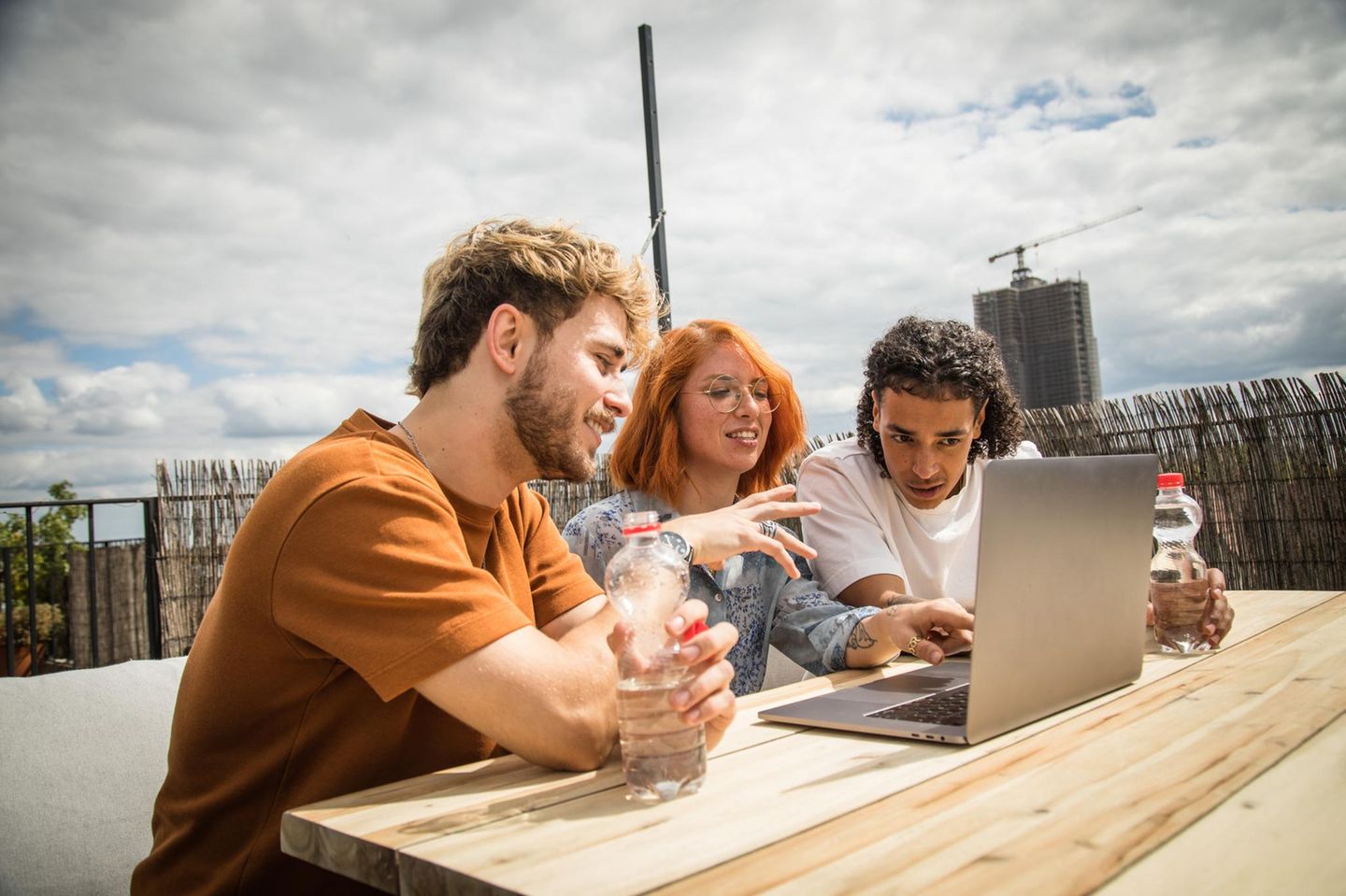1. Soziales (Duales Studium) Studenten sitzen auf einer Dachterasse und schauen in einen Laptop