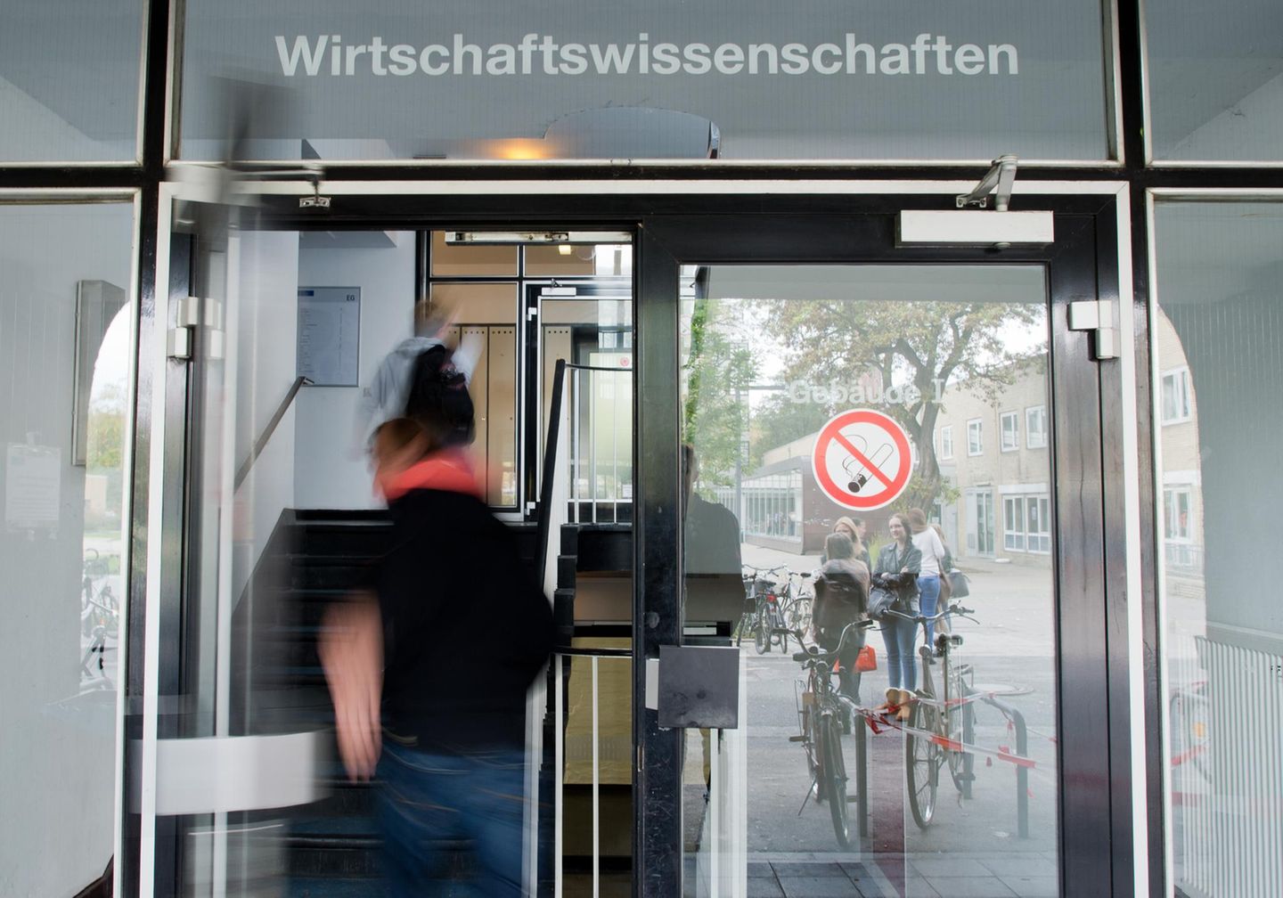 4. Wirtschaftswissenschaften (Duales Studium) Studierende betreten eine Tür, über der Wirtschaftswissenschaften steht