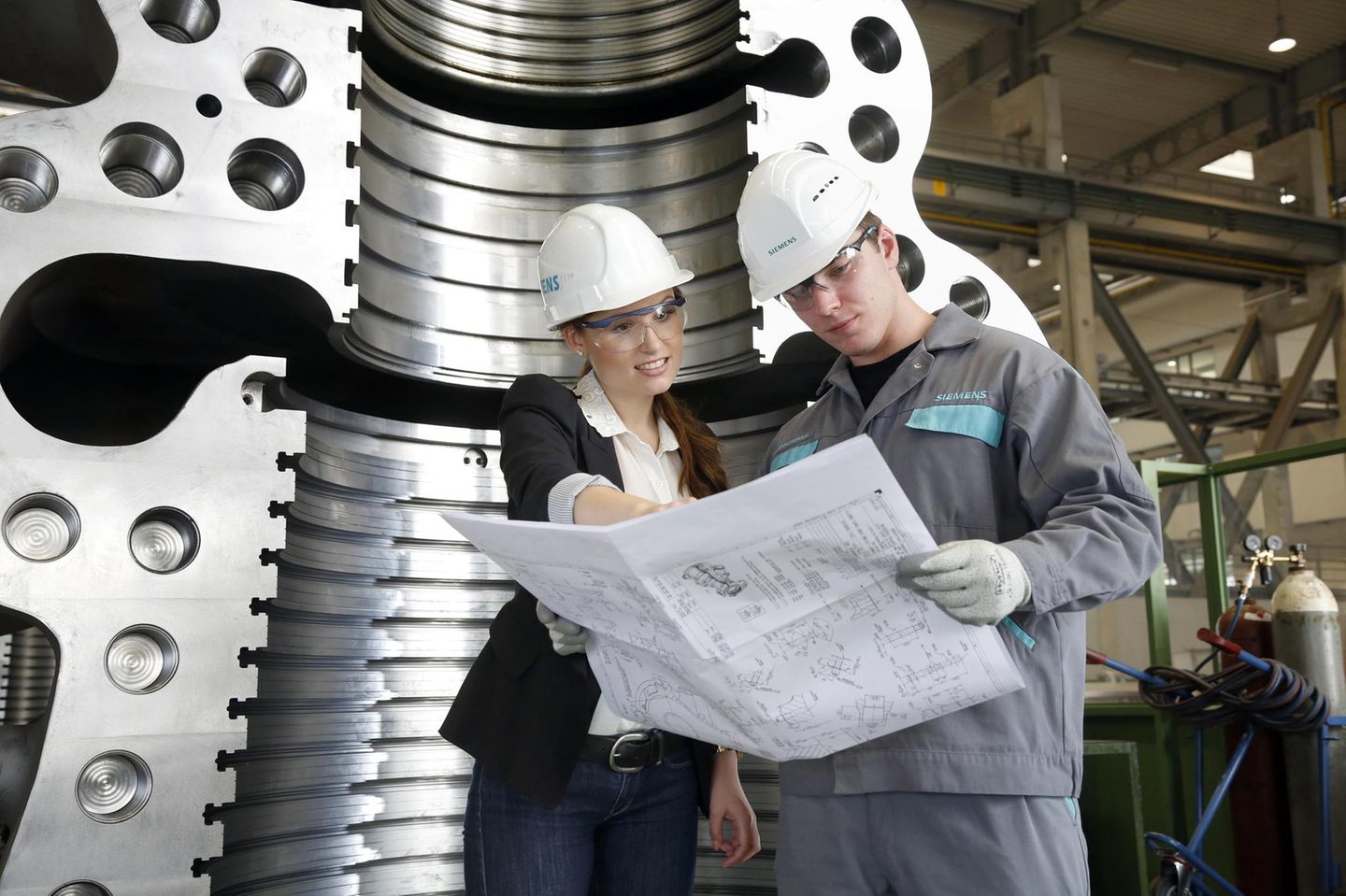 3. Ingenieur (Duales Studium) Zwei junge Ingenieure beugen sich über einen Bauplan