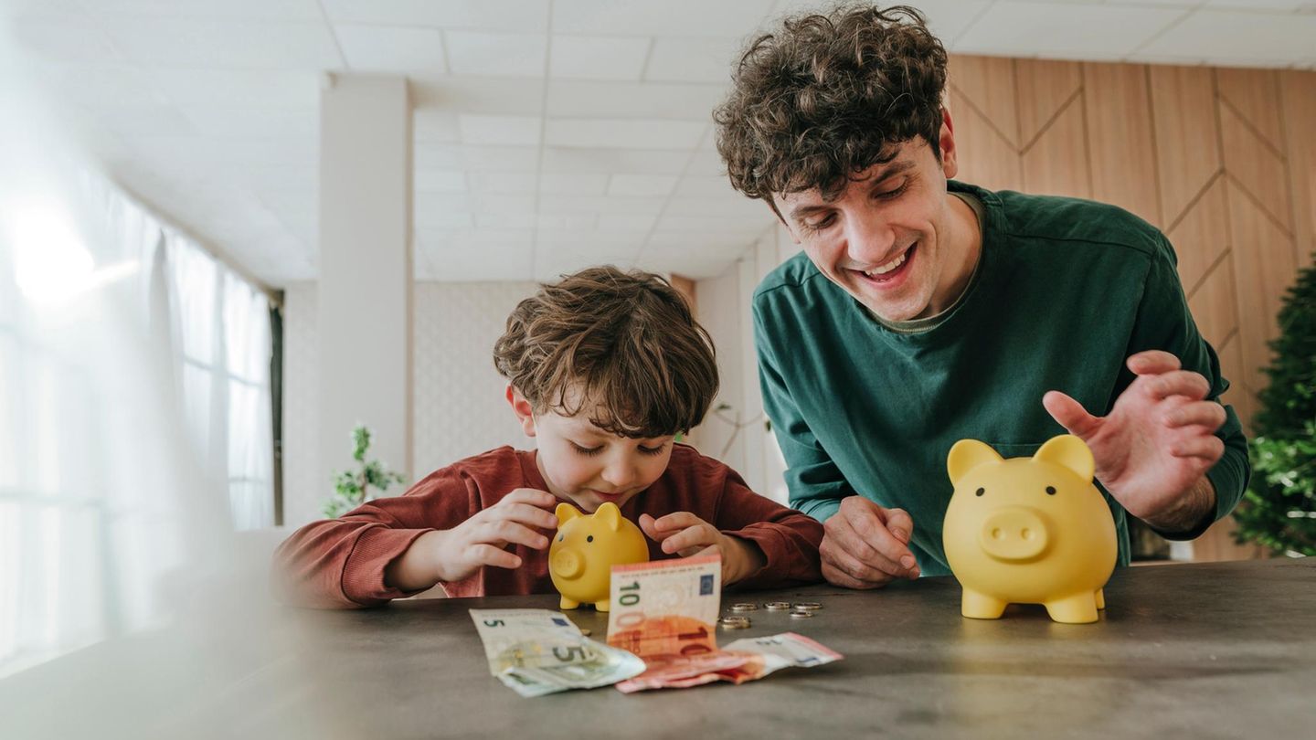 Ein Kind zählt Geld aus seinem Sparschwein Ein Kind zählt Geld aus seinem Sparschwein