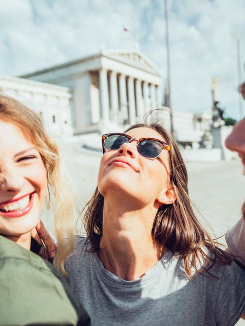 Polyamorie: Zwei Frauen und ein Mann lächeln sich im Arm