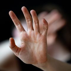 Eine Frau hält ihre Hände schützend vors Gesicht – Symbolbild Gewalt gegen Frauen