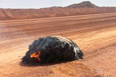 Experte in Schutzanzug begutachtet den großen Metallklumpen.