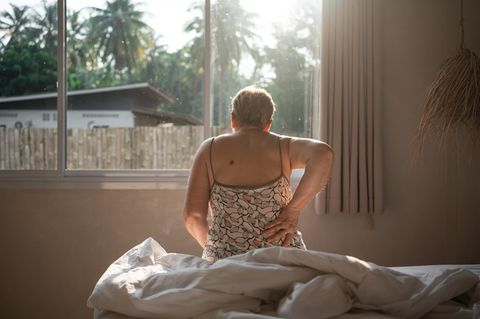 Eine ältere Frau hält sich den Rücken