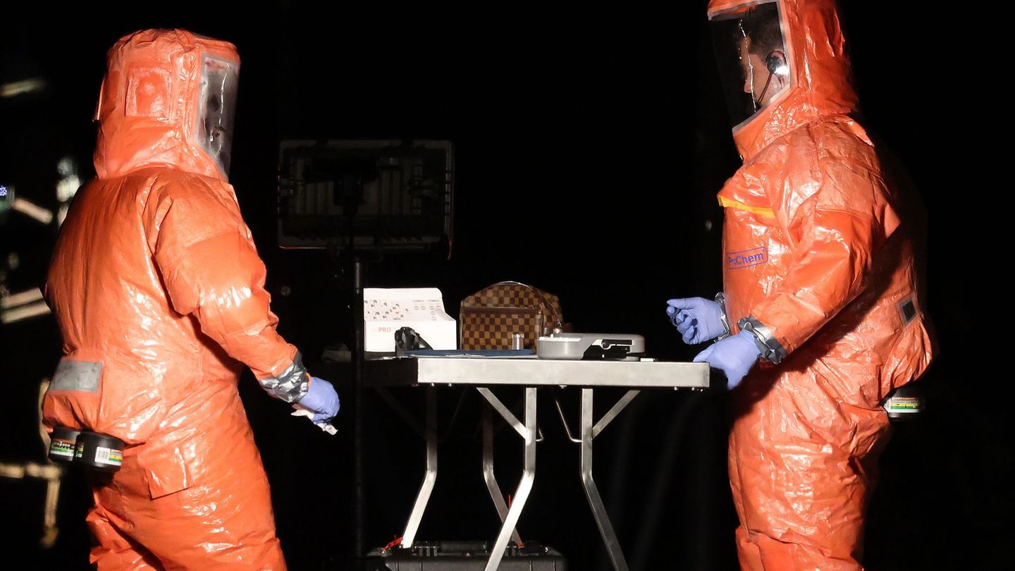 Feuerwehrleute untersuchen die Tasche mit dem undefinierten Stoff. Foto: David Young/dpa