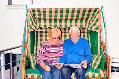Zwei Senioren in der Rente sitzen in einem Strandkorb vor einem Haus