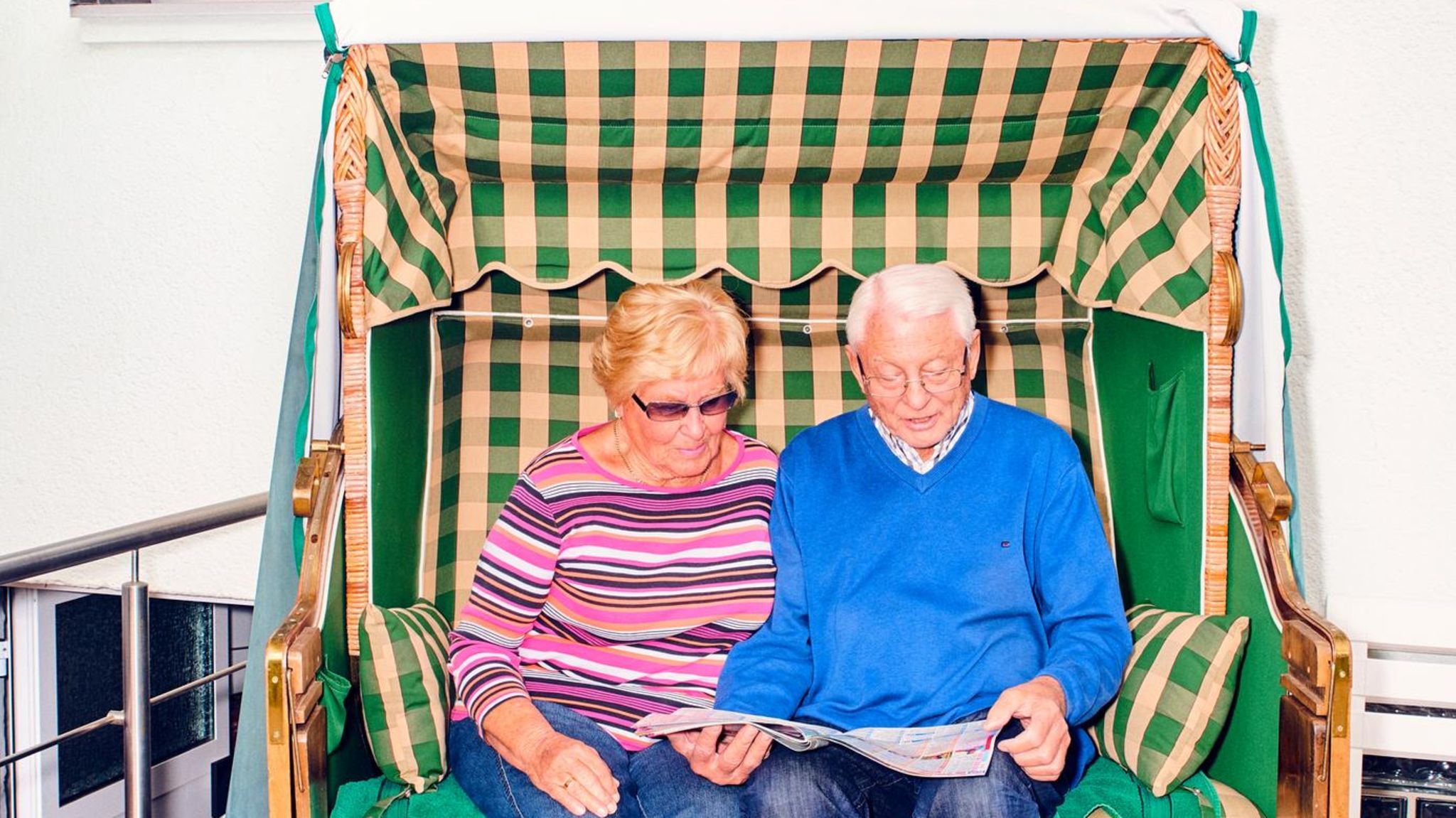 Zwei Senioren in der Rente sitzen in einem Strandkorb vor einem Haus