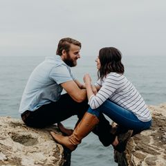 Paar sitzt auf Steinen am Meer