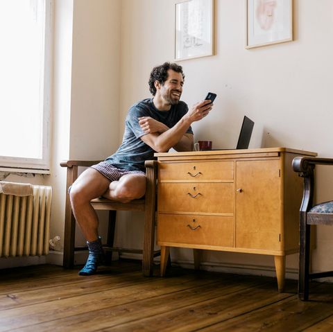 Ein Mann sitzt auf einem Stuhl und schaut lachend auf sein Smartphone