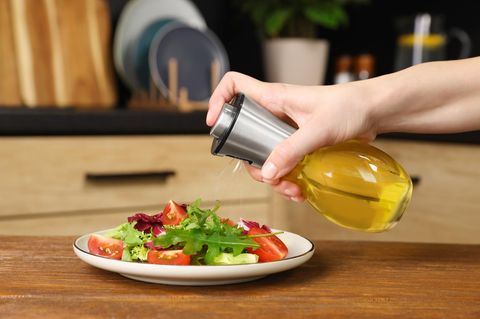 Deal Eine Frau nutzt einen Ölsprüher für ihren Salat