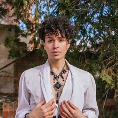 Ein androgyner junger Mann steht in einem Garten