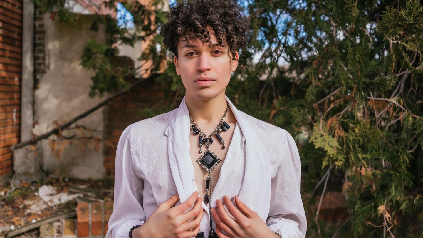 Ein androgyner junger Mann steht in einem Garten