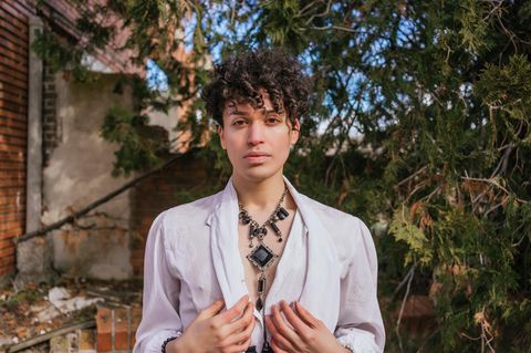 Ein androgyner junger Mann steht in einem Garten Ein androgyner junger Mann steht in einem Garten