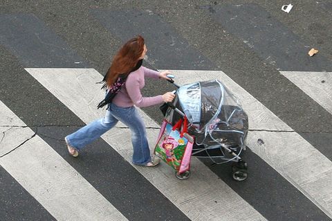 Frau mit Kinderwagen auf einem Zebrastreifen