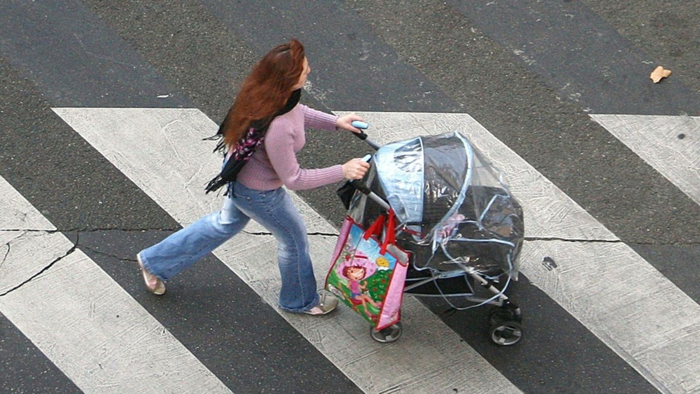 Frau mit Kinderwagen auf einem Zebrastreifen Frau mit Kinderwagen auf einem Zebrastreifen