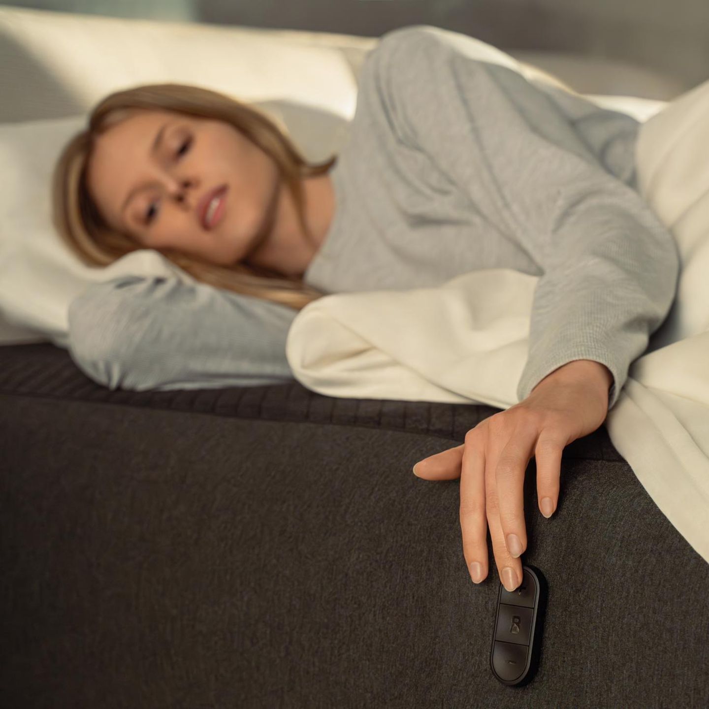 Eine Frau liegt auf der smarten Matratze Eight Sleep Pod und steuert sie mit Buttons an der Seite