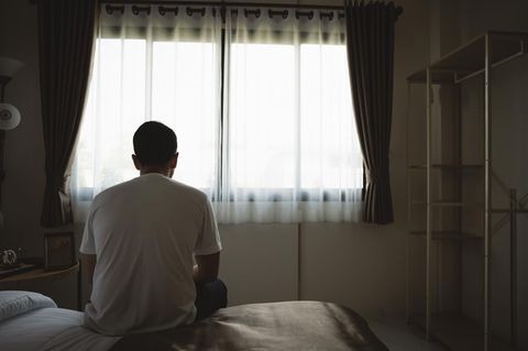 Junger Mann sitzt auf einer Bettkante