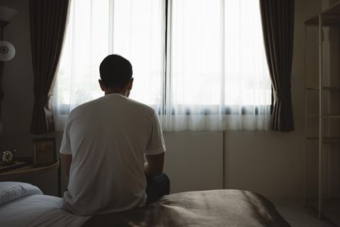Junger Mann sitzt auf einer Bettkante Junger Mann sitzt auf einer Bettkante