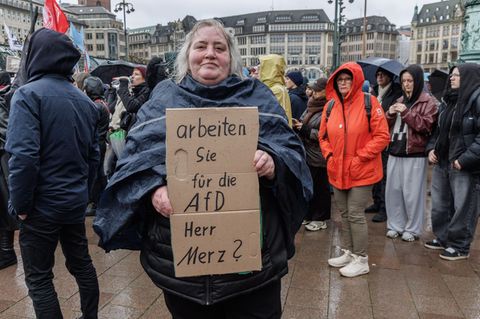Eine Demonstrantin in Hamburg stellt auf einem Pappschild eine Frage an Bundeskanzler Friedrich Merz (CDU). Foto: Markus Scholz/