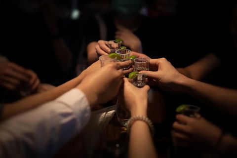 Menschen stoßen mit Tequila an