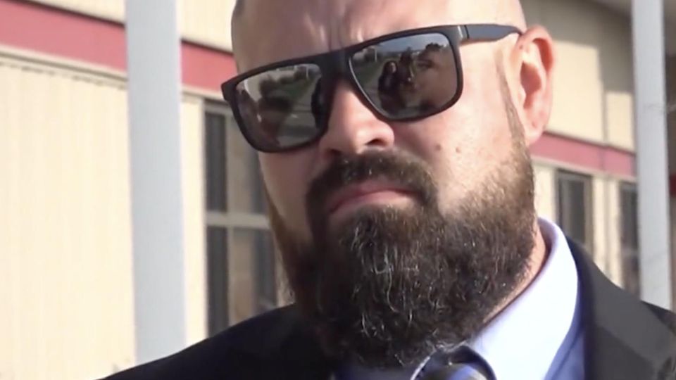 Familienvater bewirbt sich um das Amt des Sheriffs – trotz Mordanklage Aaron Spencer vor einer Gerichtsverhandlung mit Sonnenbrille und ernster Mine.