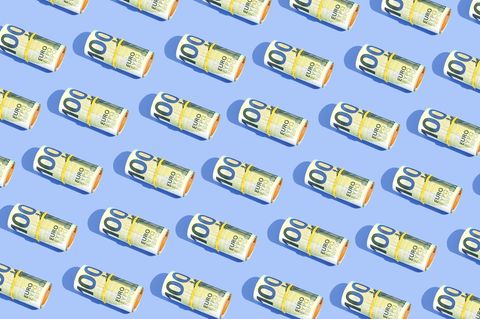 Geldscheine liegen symetrisch gerollt auf blauem Untergrund