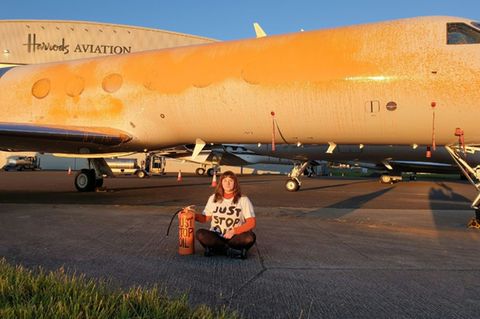 Klimaaktivistin vor mit Farbe besprühtem Privatjet