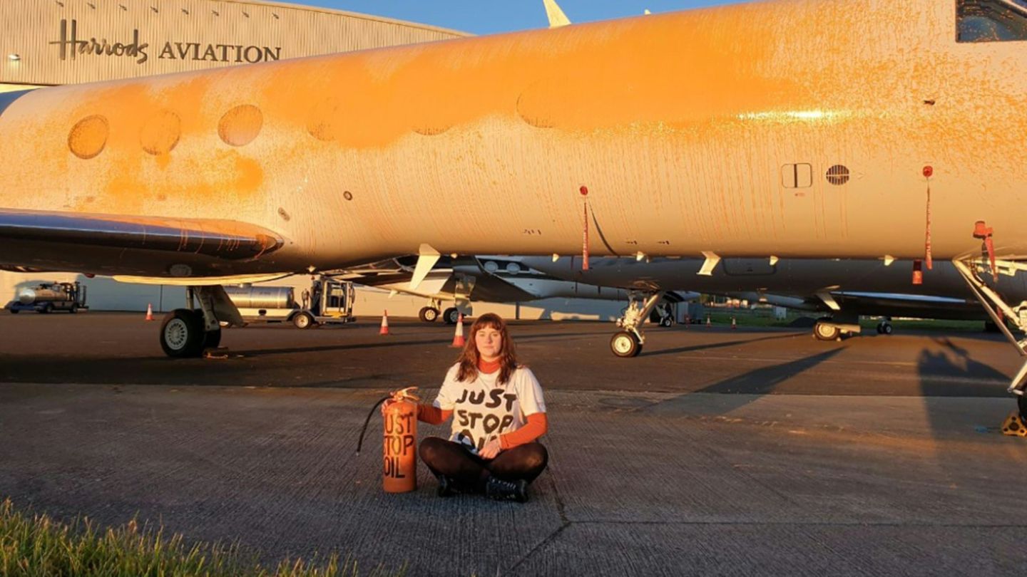 Klimaaktivistin vor mit Farbe besprühtem Privatjet Klimaaktivistin vor mit Farbe besprühtem Privatjet