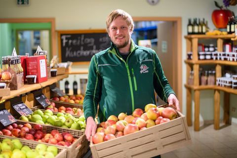 André Stallbaum vom Stendaler Scheunenladen steht mit einer Kiste Äpfel in seinem Hofladen. Foto: Klaus-Dietmar Gabbert/dpa