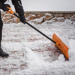 Nach einem Schneefall entfernt eine Person Schnee vor dem Haus