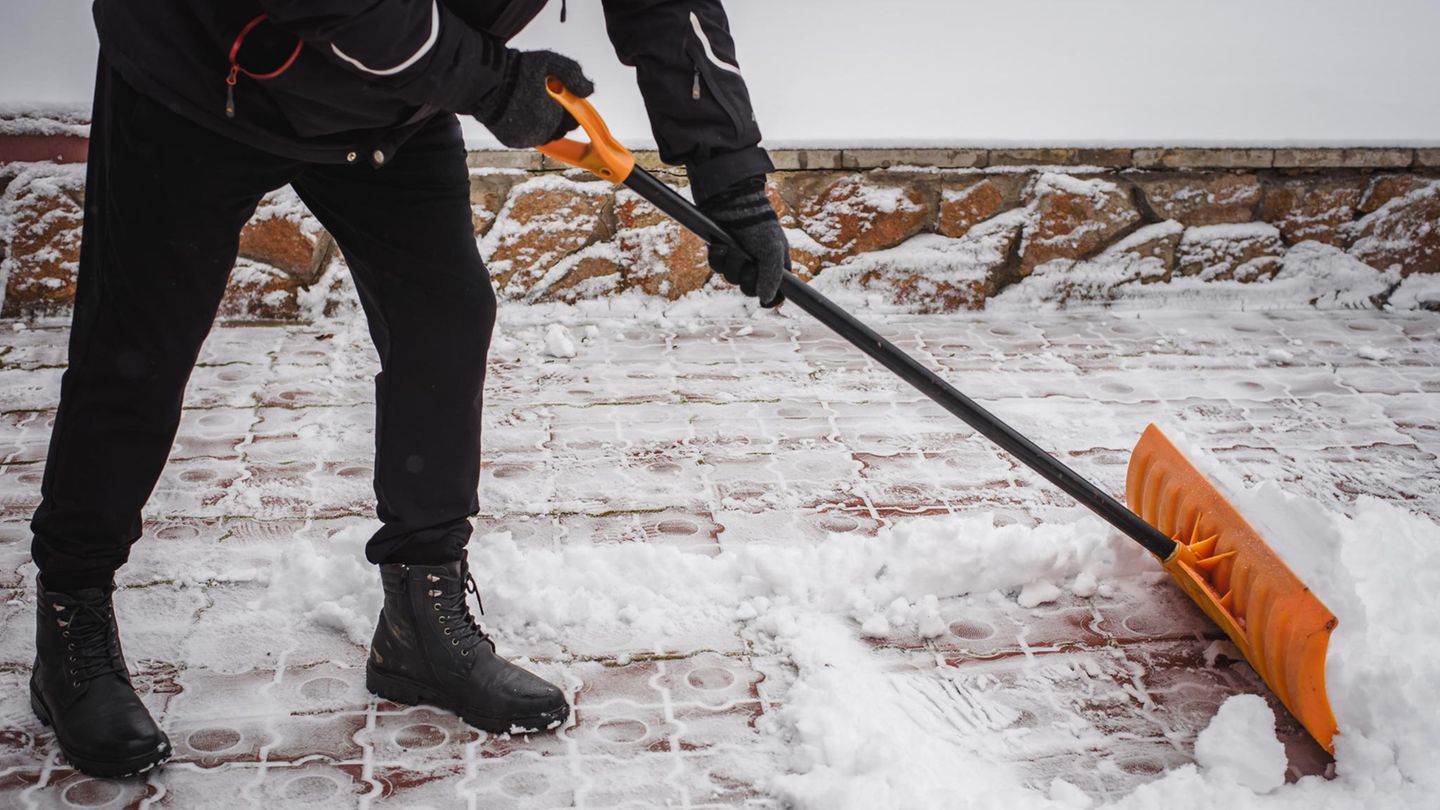 Schneeschieber Nach einem Schneefall entfernt eine Person Schnee vor dem Haus